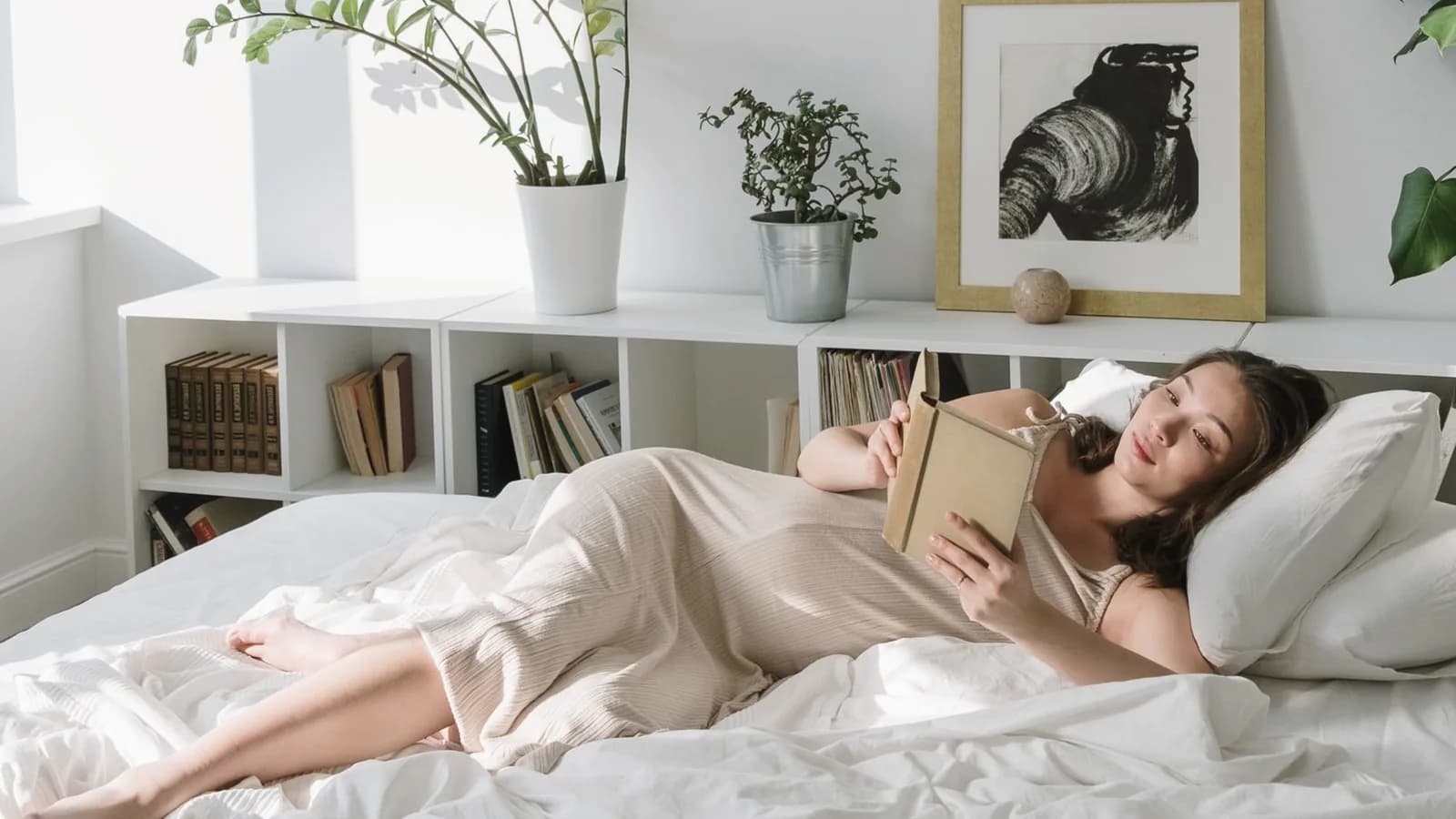 Are elective ultrasounds safe: Pregnant woman reading a book on a bright bed in a calm minimalist bedroom