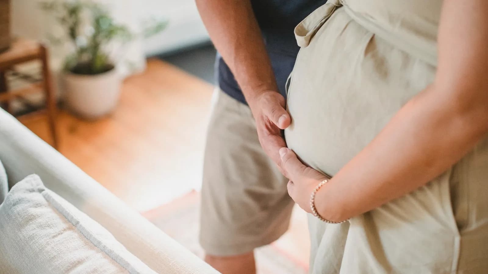 Dad attending ultrasound appointments: Partner and pregnant woman touching her belly together in a sunny home