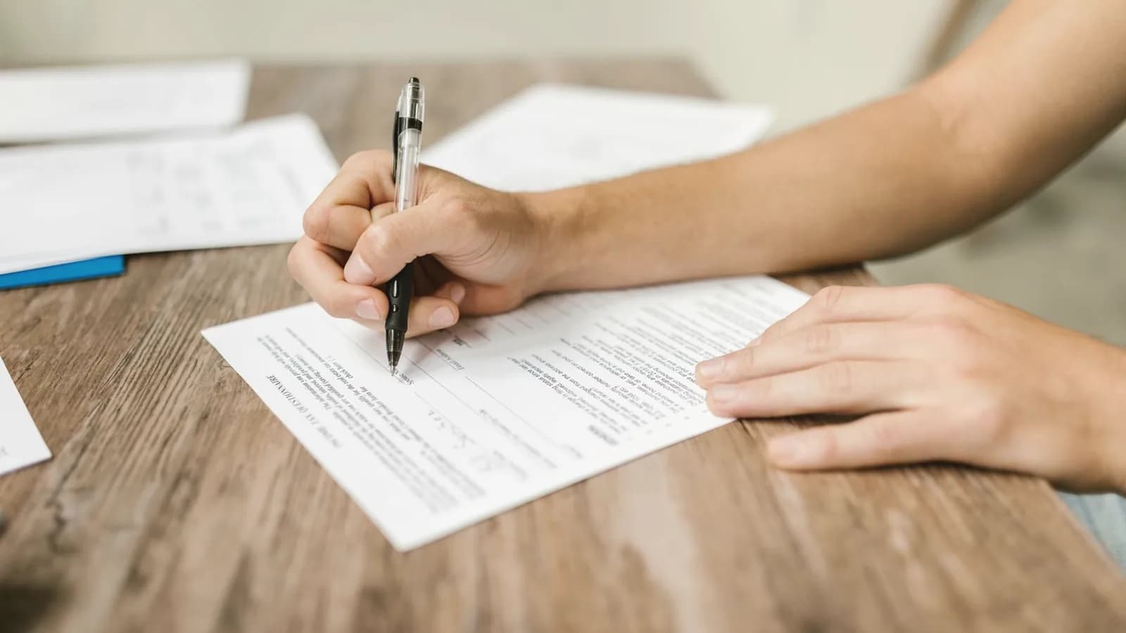 Does insurance cover elective ultrasounds: Close-up of a hand signing paperwork with a pen on a wooden table