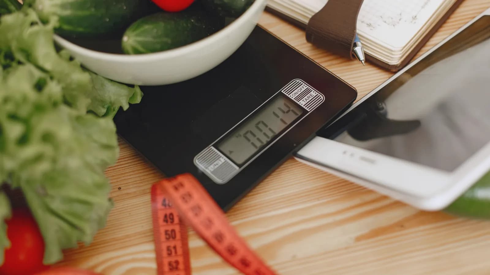 Healthy weight gain during pregnancy: Fresh vegetables in a bowl beside a kitchen scale and measuring tape