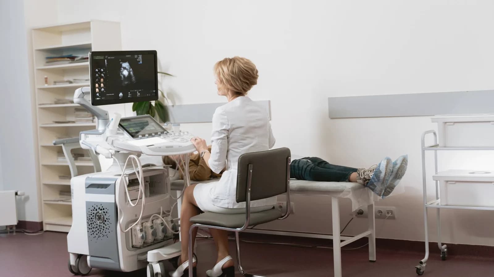 How ultrasound technology works: Sonographer at a modern ultrasound machine with patient resting in a bright clinic room
