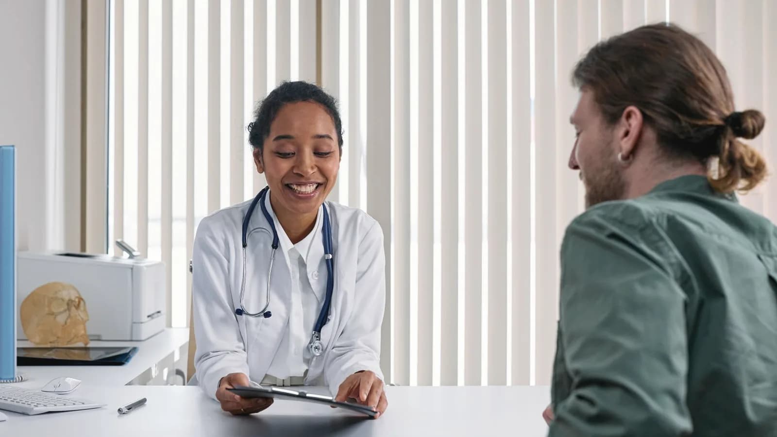 Medical vs elective ultrasound: Smiling doctor in a white coat reviewing a plan with a patient