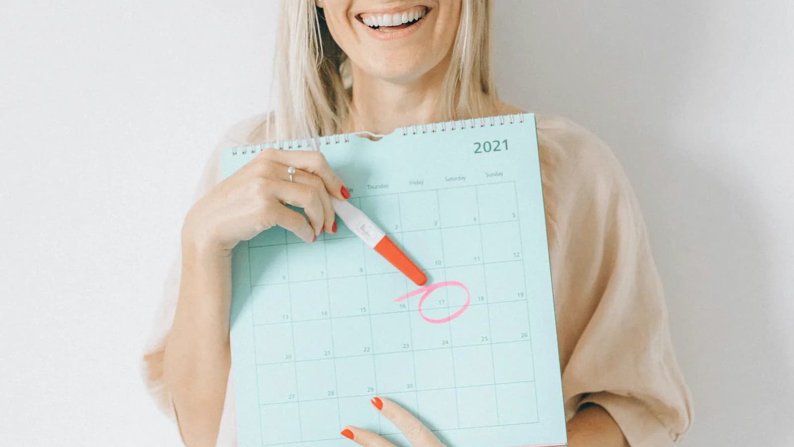 Pregnancy ultrasound schedule by week: Smiling woman in a soft linen top marking a date on a paper calendar