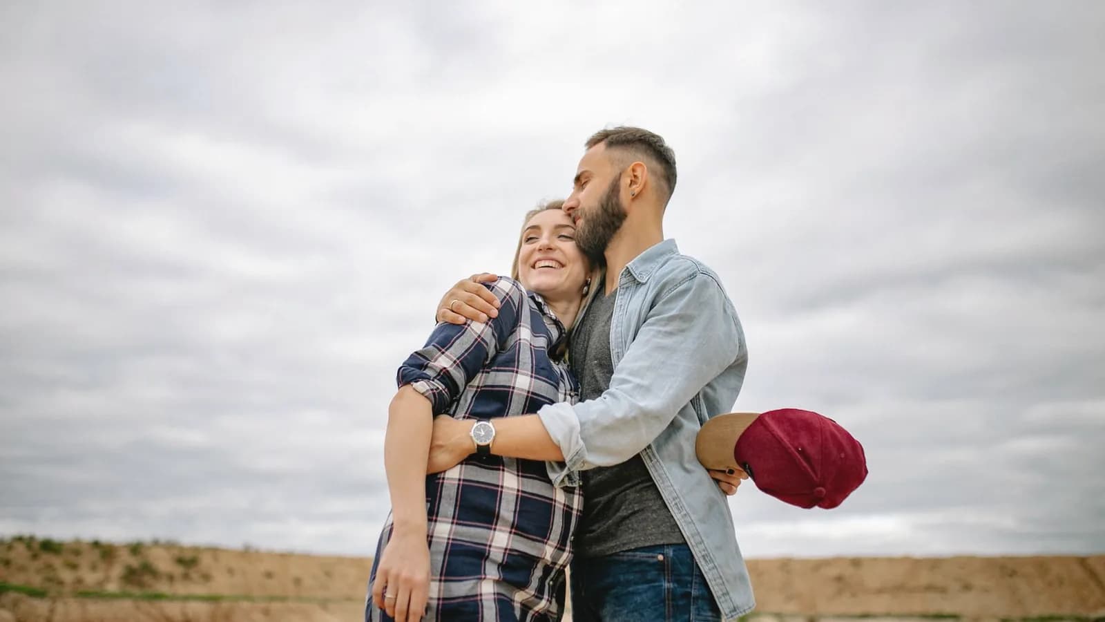 Prenatal depression support: Smiling couple hugging outdoors, the man holding his pregnant partner close