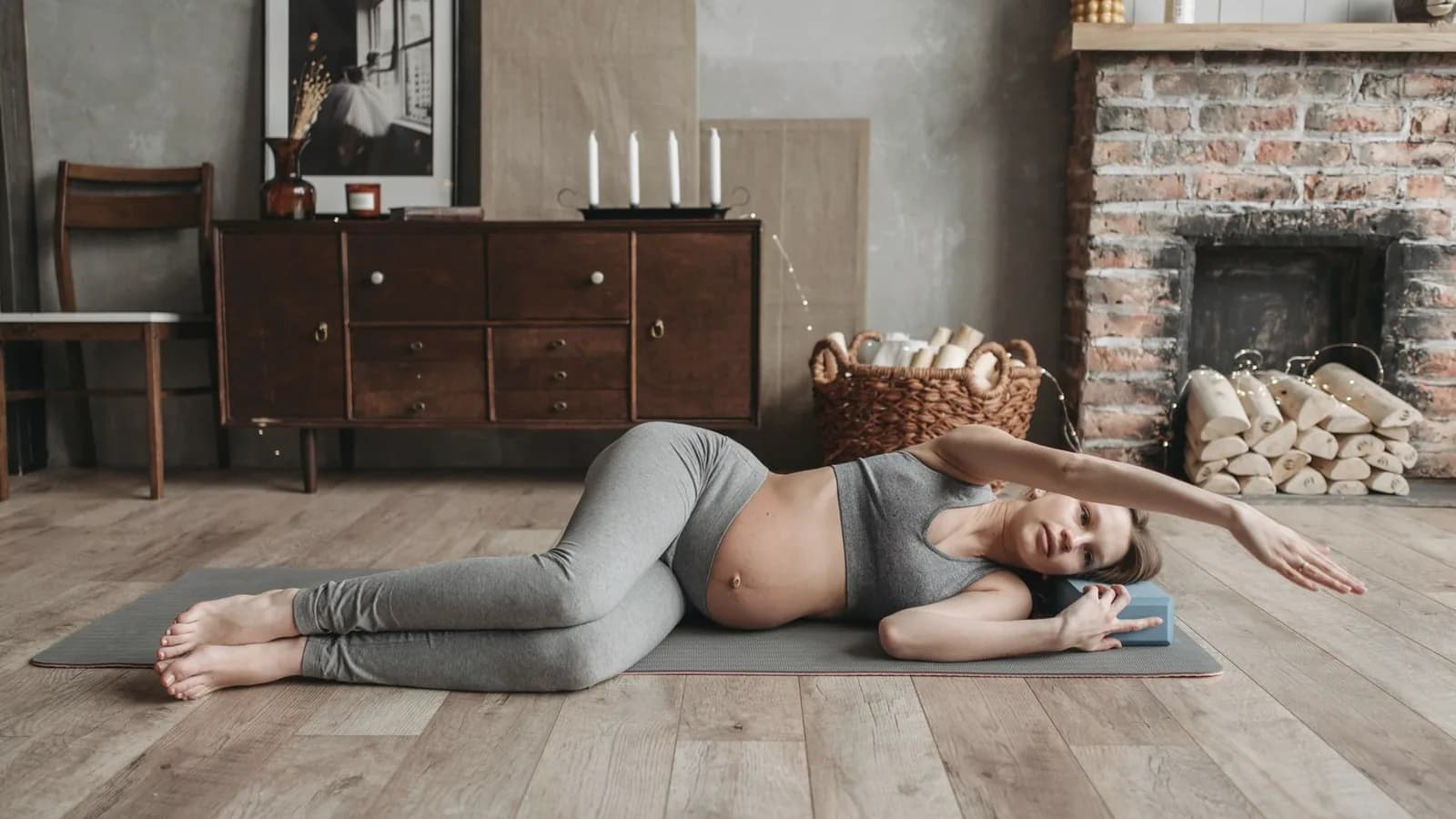 Prenatal yoga benefits: Pregnant woman stretching gently on a yoga mat in a warm living room