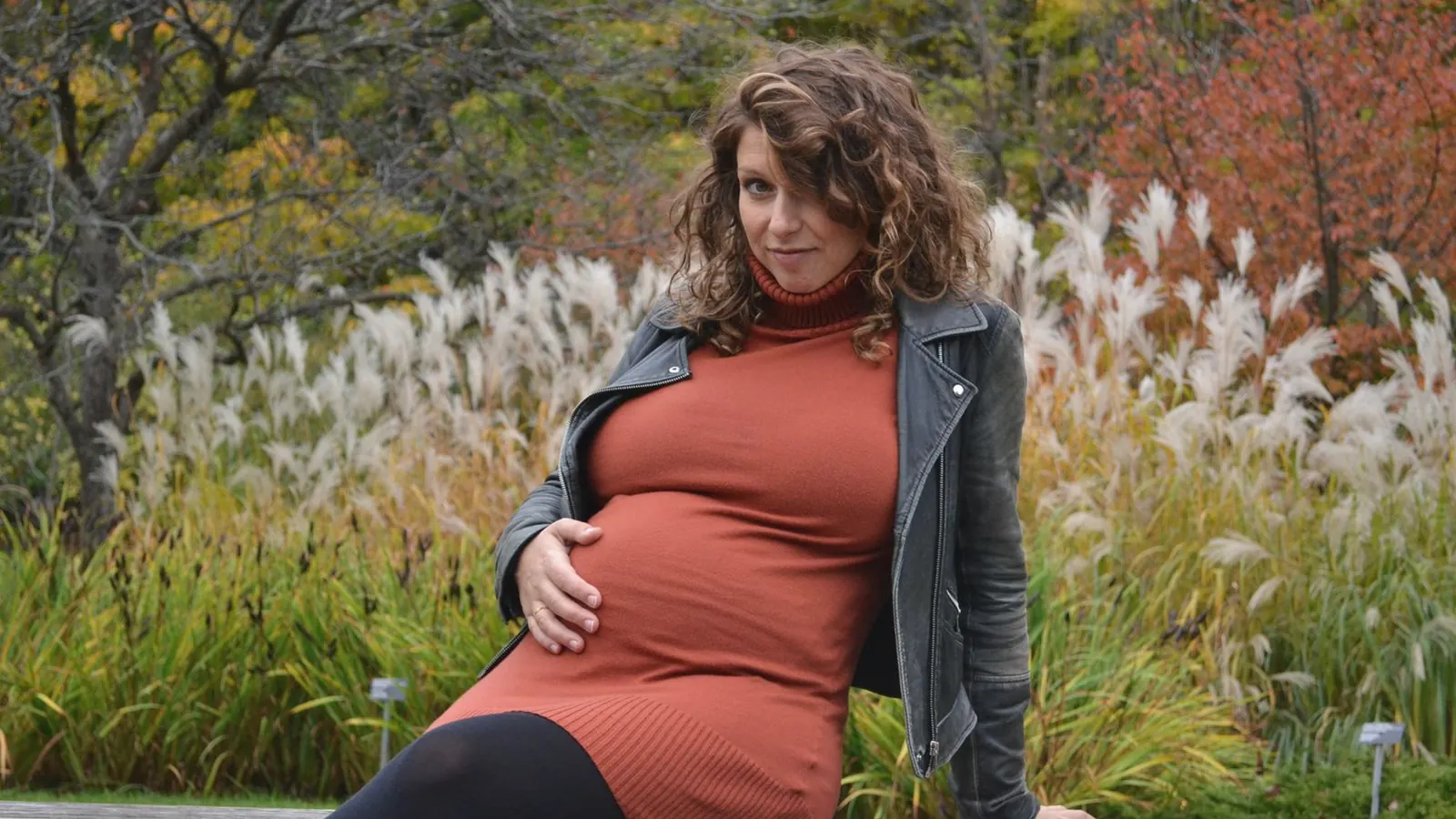 Best time for 3D ultrasound at 28 weeks: Smiling pregnant woman in a rust dress sitting in an autumn park