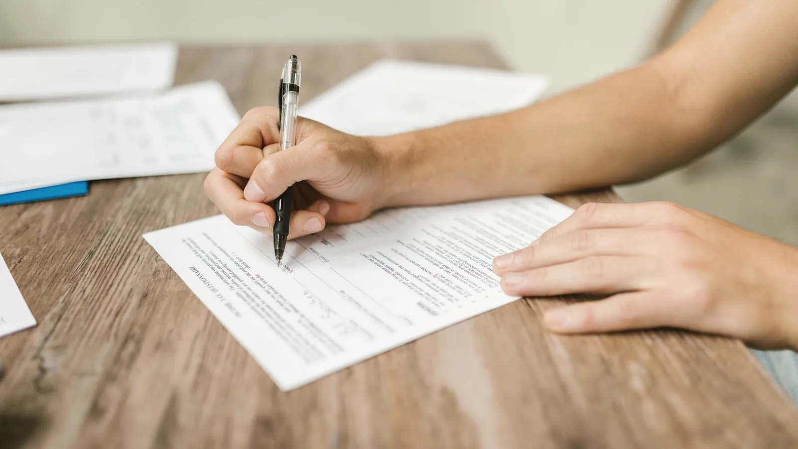 Does insurance cover elective ultrasounds: Close-up of a hand signing paperwork with a pen on a wooden table