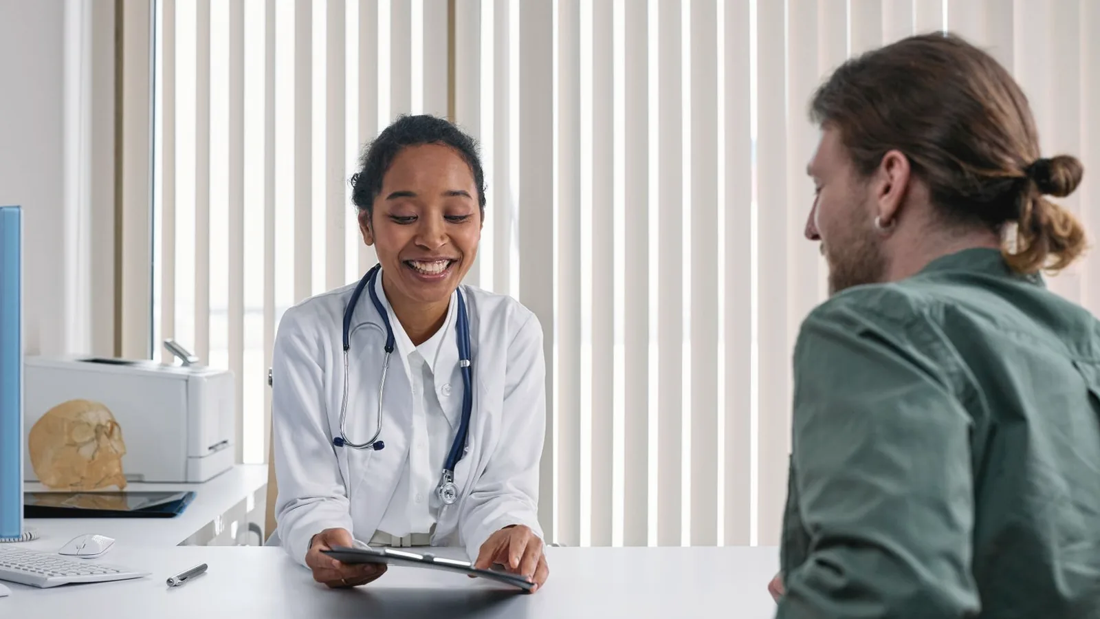 Medical vs elective ultrasound: Smiling doctor in a white coat reviewing a plan with a patient