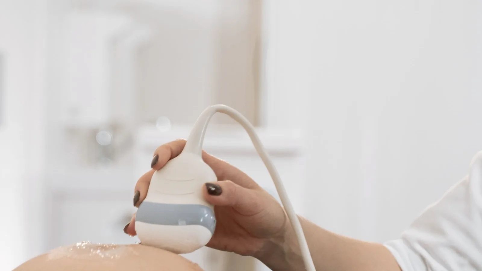 Nub theory gender prediction: Ultrasound probe on a pregnant belly during a scan at a clinic