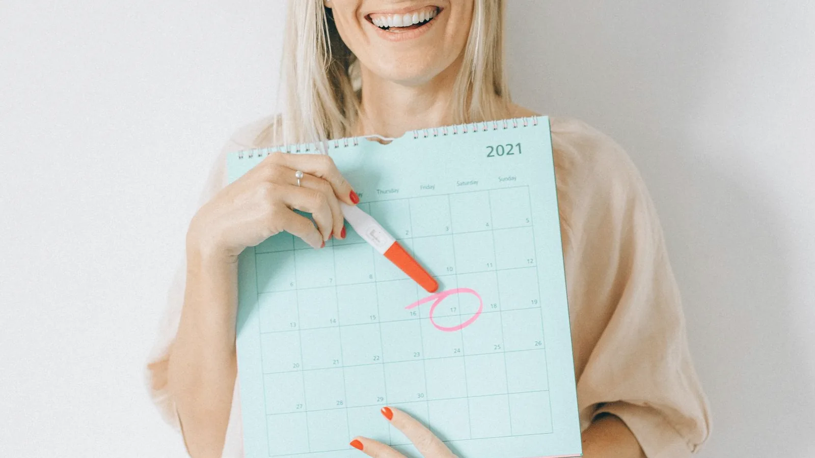 Pregnancy ultrasound schedule by week: Smiling woman in a soft linen top marking a date on a paper calendar