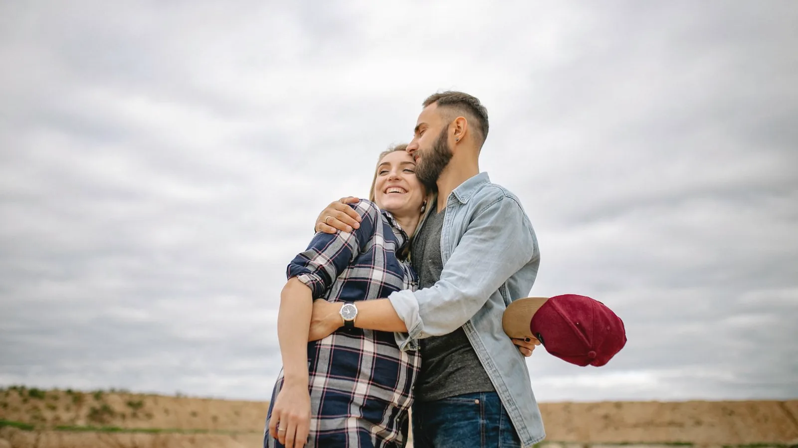 Prenatal depression support: Smiling couple hugging outdoors, the man holding his pregnant partner close