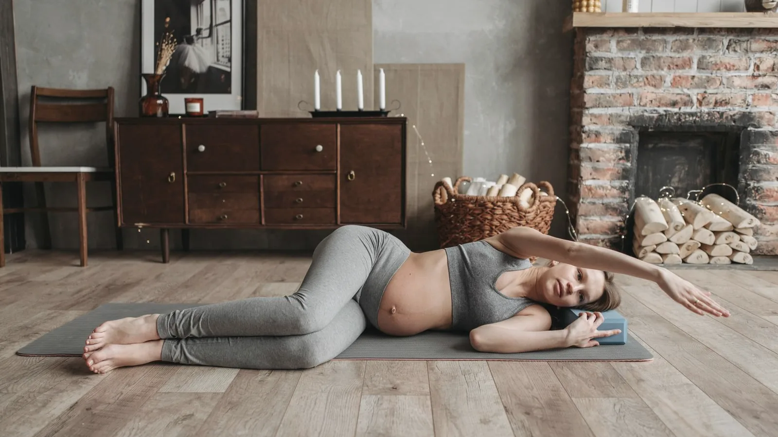 Prenatal yoga benefits: Pregnant woman stretching gently on a yoga mat in a warm living room