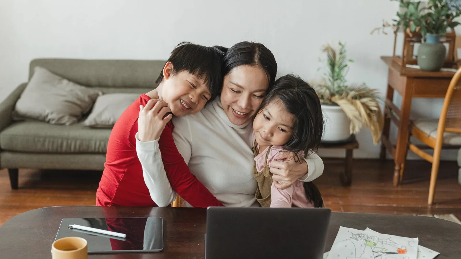 Ultrasound services in Spanish Raleigh: Smiling mother hugging her two children at a table in a bright living room